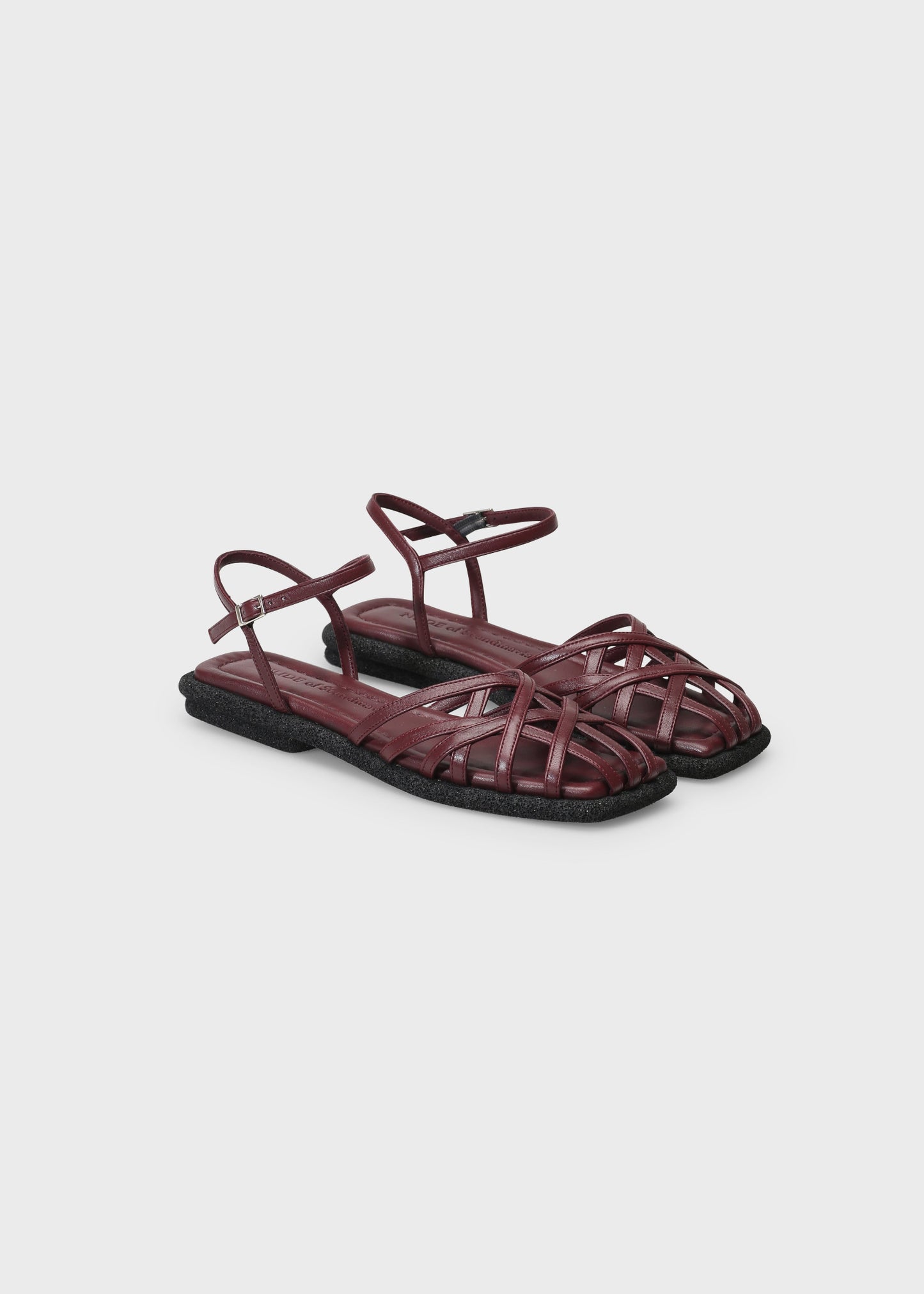 Pair of maroon sandals on a light gray background
