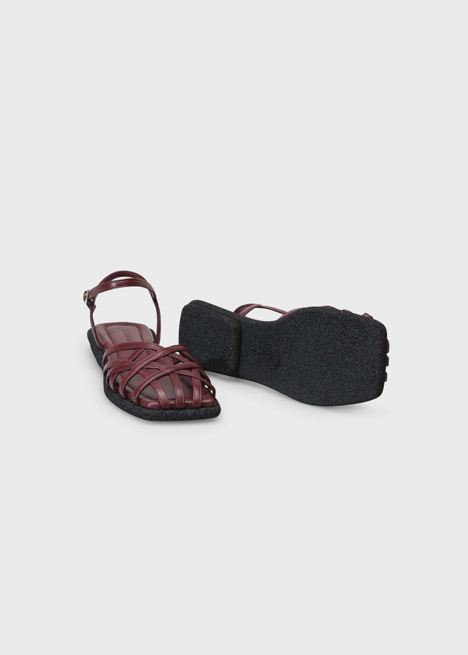 Maroon sandal with a black sole on a light gray background